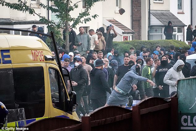 Rioters wearing masks throw missiles at police officers in Southport