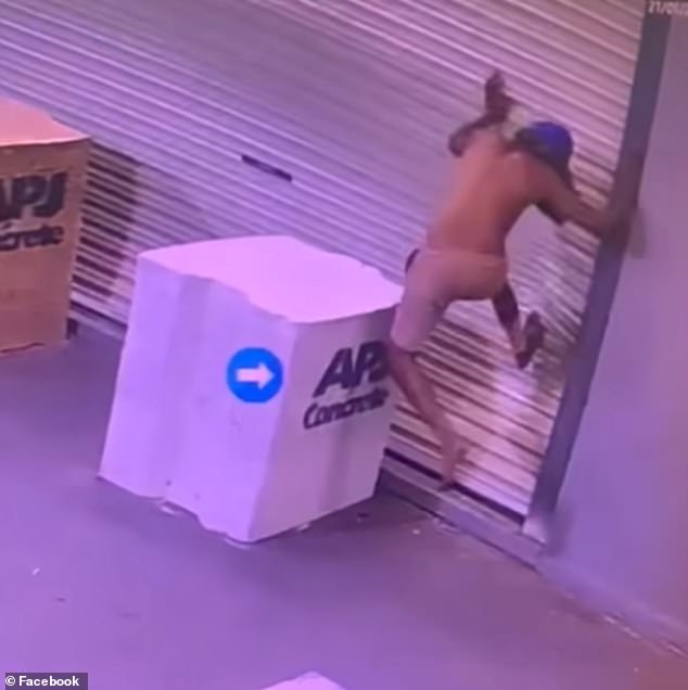 The young man slams his feet against the door of the liquor store.