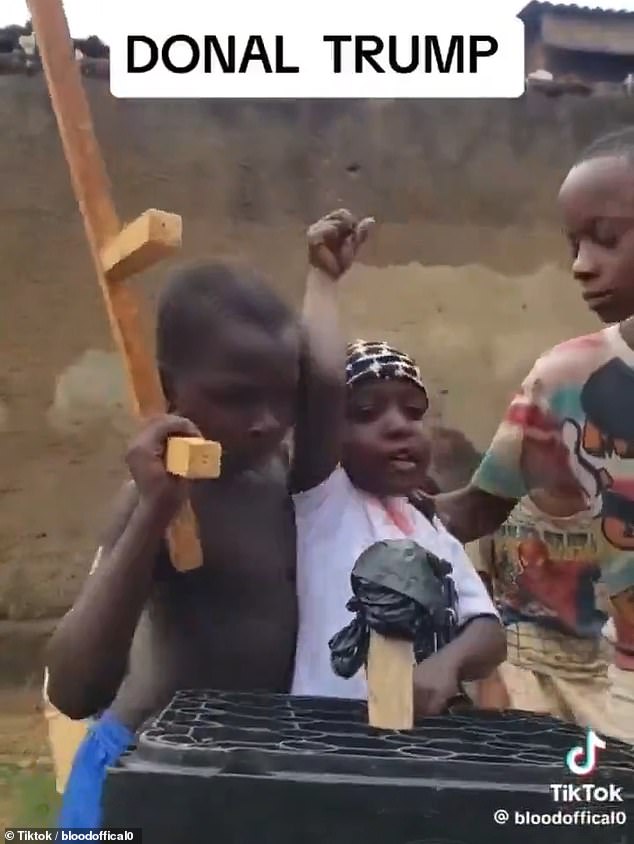 Using wooden rifles and a lectern made of plastic boxes, Ugandan children satirically reenacted the shooting as the leader raised his fist in the air and shouted 