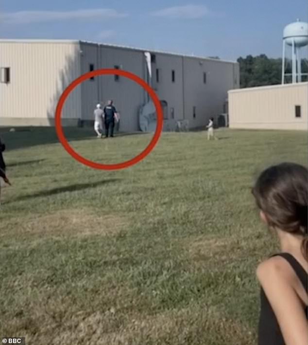 A member of the public is seen speaking to a police officer before shots rang out, the building where Crooks was is on the right.