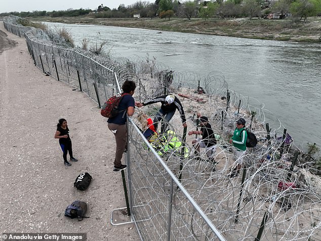 A group of illegal immigrants scale a fence near Eagle Pass, Texas