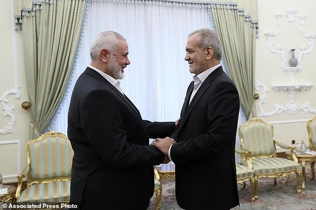 In this photo released by Iran's Presidential Office, President Masoud Pezeshkian, right, shakes hands with Hamas chief Ismail Haniyeh at the start of their meeting at the president's office in Tehran, Iran, Tuesday, July 30, 2024. (Iranian Presidential Office via AP)