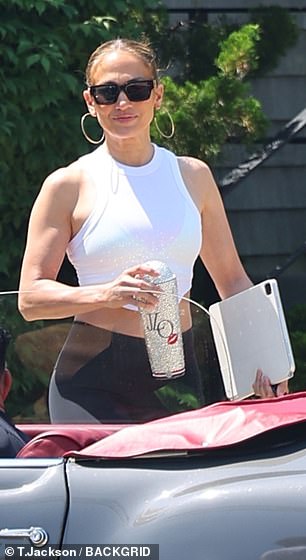 The producer and Atlas star rocked a white halterneck crop top and black leggings while holding a laptop and her dazzling JLo cup.