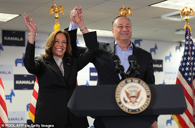 Vice President Kamala Harris (left) and second gentleman Doug Emhoff (right) hold hands before a crowd of campaign staffers, after President Joe Biden called during Harris' visit on Monday and said her decision to drop out of the race was the best thing to do.