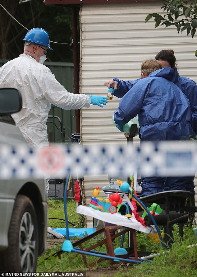 Pictured: Forensic experts hold a second bottle of tea-brown liquid, during an investigation into the cause of the fire.