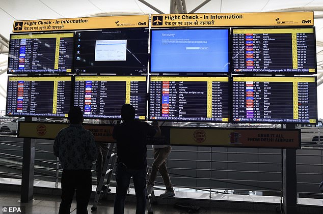 Indian workers try to repair a faulty information screen at Delhi International Airport in New Delhi, India