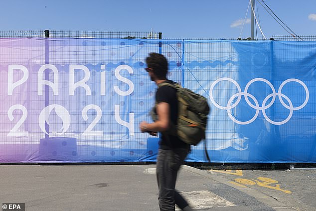 A man walks past a sign with the Paris 2024 logo in Paris, France, July 17, 2024.