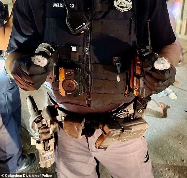 A Columbus police officer is seen holding the two hamsters found in Pancake's pockets.