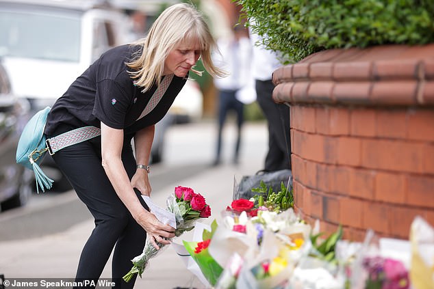 A woman leaves flowers near the scene in Southport this morning following yesterday's incident.