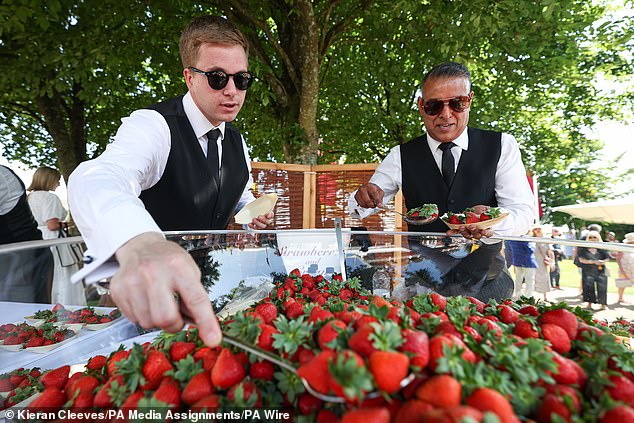 Staff members serve strawberries and cream to guests.