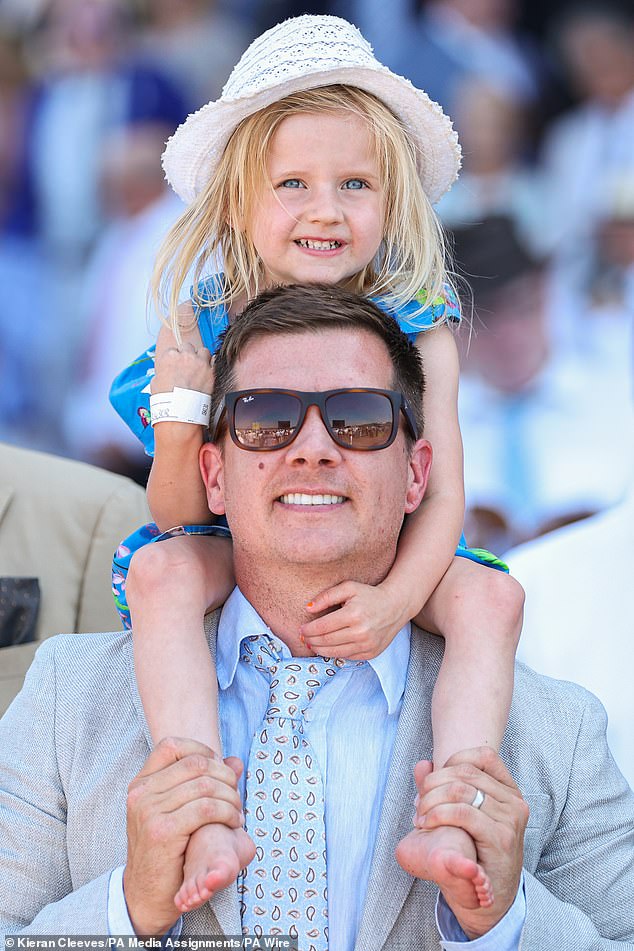 A race fan, but with a little girl on his shoulders to get the best view of the race.