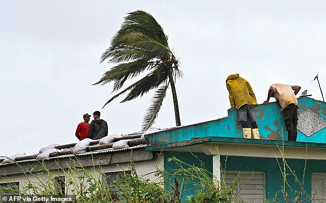 Cubans repair a roof in San Juan y Martinez, Pinar del Rio province, on September 27, 2022 after the passage of Hurricane Ian