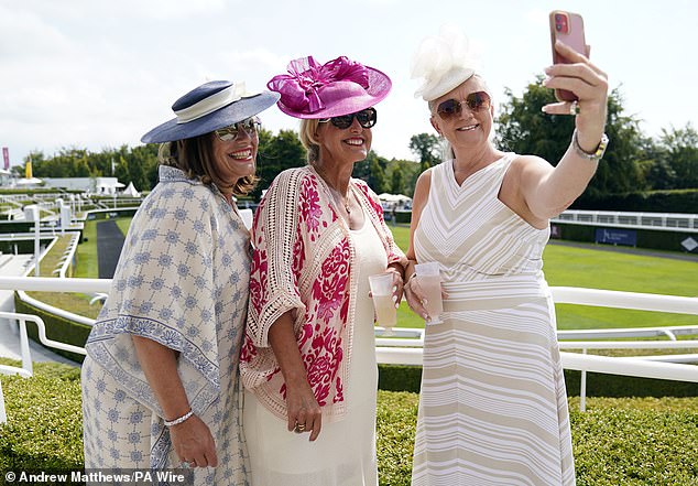 A group of women in elegant headdresses pose for a selfie at the Goodwood grounds today