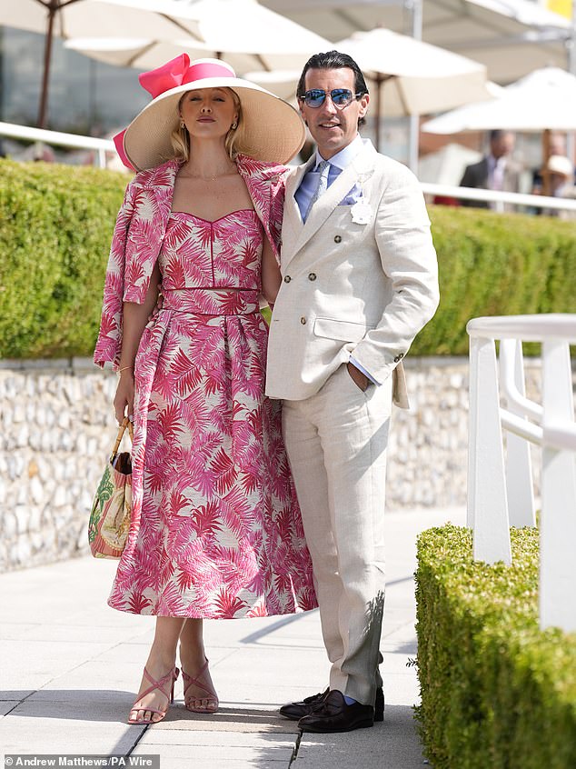 An elegant woman dressed in pink and white poses next to an elegant man in a white and blue suit.