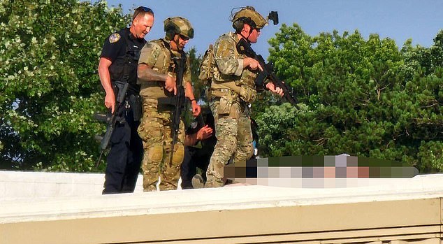 Law enforcement personnel stand over Crooks' body on the roof of America Glass Research, located just a couple hundred yards from where Trump was speaking.