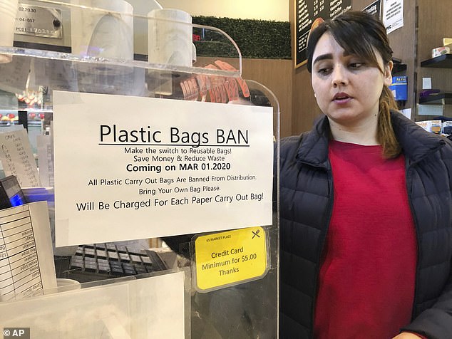 A cash register employee looks at a sign that says "Ban on plastic bags" At a grocery store in New York on Wednesday, February 26, 2020. Many types of plastic bags will be banned starting March 1, 2020 in New York State in an effort to reduce pollution.