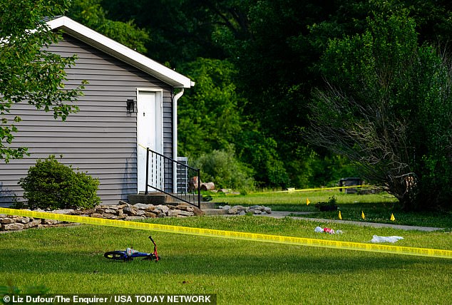 A child's bicycle, along with evidence markers, in the front yard of the home in Monroe Township