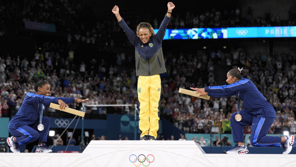 Silver medalist Simone Biles of the United States, left, and bronze medalist Jordan Chiles of the United States, right, greet gold medalist Rebeca Andrade of Brazil during the medal ceremony for the women's artistic gymnastics individual all-around floor final at the Arena Bercy at the 2024 Summer Olympics, Monday, Aug. 5, 2024, in Paris, France. (AP Photo/Abbie Parr)