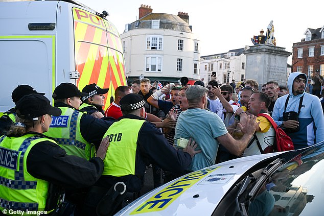 Police hold back anti-immigration protesters during a confrontation on the seafront, on August 4, 2024 in Weymouth