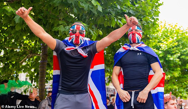 Two men hide their features with Union Jack masks, hiding the faces of cowards.