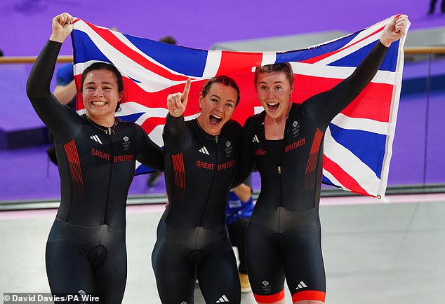 The Team GB cycling squad, consisting of Sophie Capewell, Katy Marchant and Emma Finucane, proudly raise a celebratory flag.