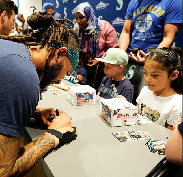 Mariners shortstop JP Crawford signs a card for kids before Tuesday's game