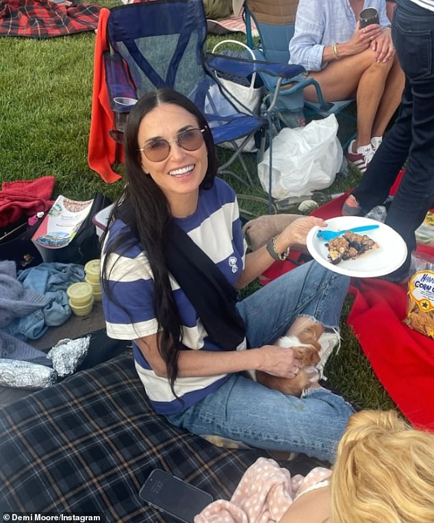 Brat Packer, 60, looking like a teenager in her striped T-shirt and jeans, cradled her beloved two-year-old Chihuahua, Pilaf, also known as Little Mouse, as she relaxed on a plaid mattress on the grass.