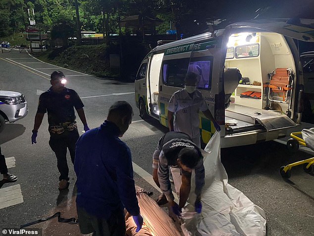 Emergency services load the body of a Thai tour guide who died due to floodwaters in the cave into an ambulance.