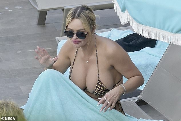 Ashley, who bears a striking resemblance to Pippen, 50, showed off her bust in a printed strappy bikini as she chatted while relaxing on a sun lounger.