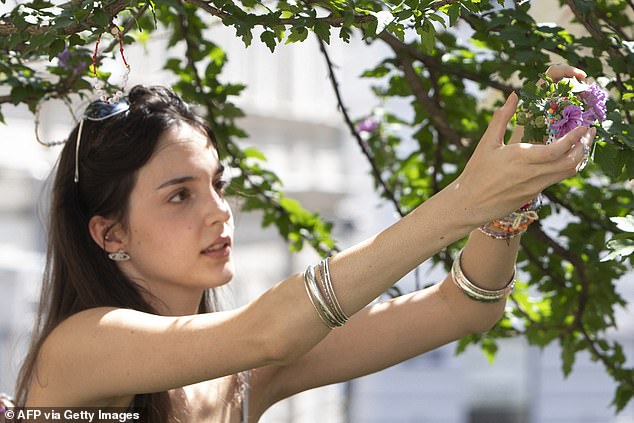 A Taylor Swift fan arranges her beaded bracelets at the Swiftie Tree on Cornelius Strasse