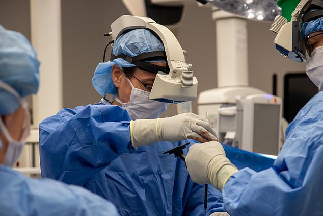 The headset allows surgeons to see the real world but with virtual screens superimposed in front of them displaying vital information, known as augmented reality.