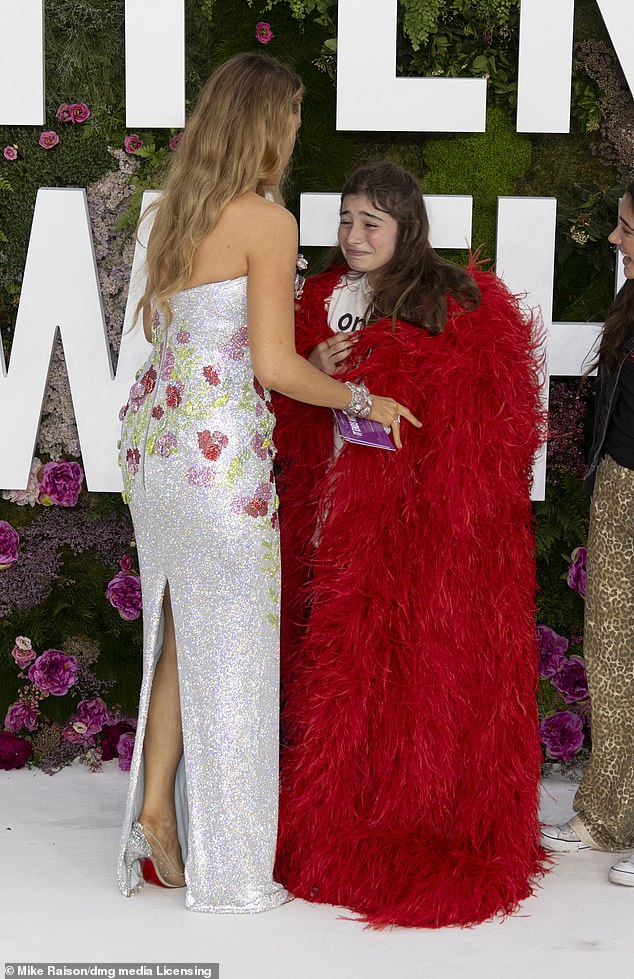 The Hollywood star, wearing shiny silver Louboutins, gifted her luxurious red coat to a young fan.