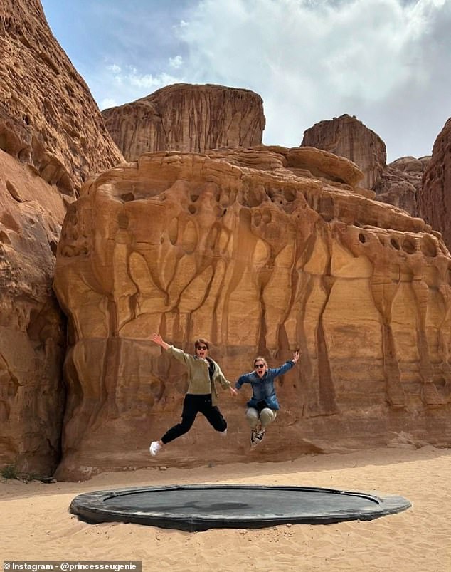 This photograph, which was taken in the same desert location as the first, shows the two smiling sisters holding hands in a pose in the air.