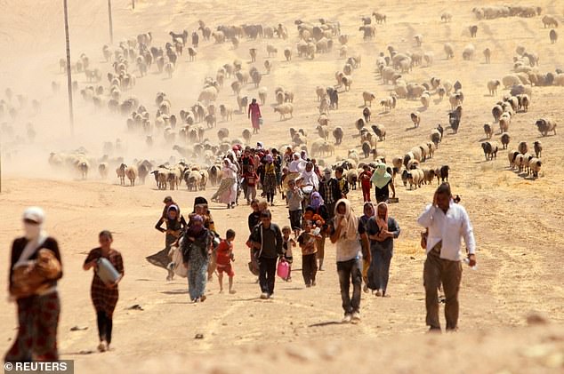 Displaced Yazidis fleeing IS violence walk towards the Syrian border in 2014