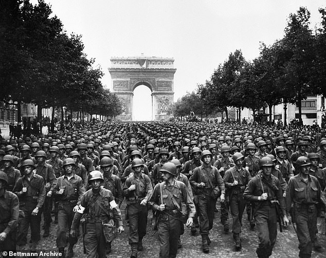 American troops marching down the Champs-Élysées in Paris with the Arc de Triomphe in the background