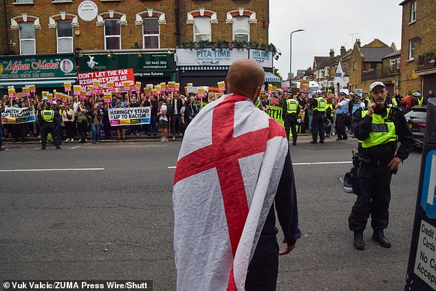 A man holding an England flag looks out at a large crowd of anti-racism protesters in Finchley.