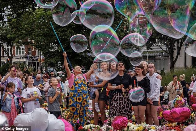 Community members, family and friends blow bubbles as people gather to mourn the victims of the harrowing knife attack by holding a vigil near Atkinson on August 5.