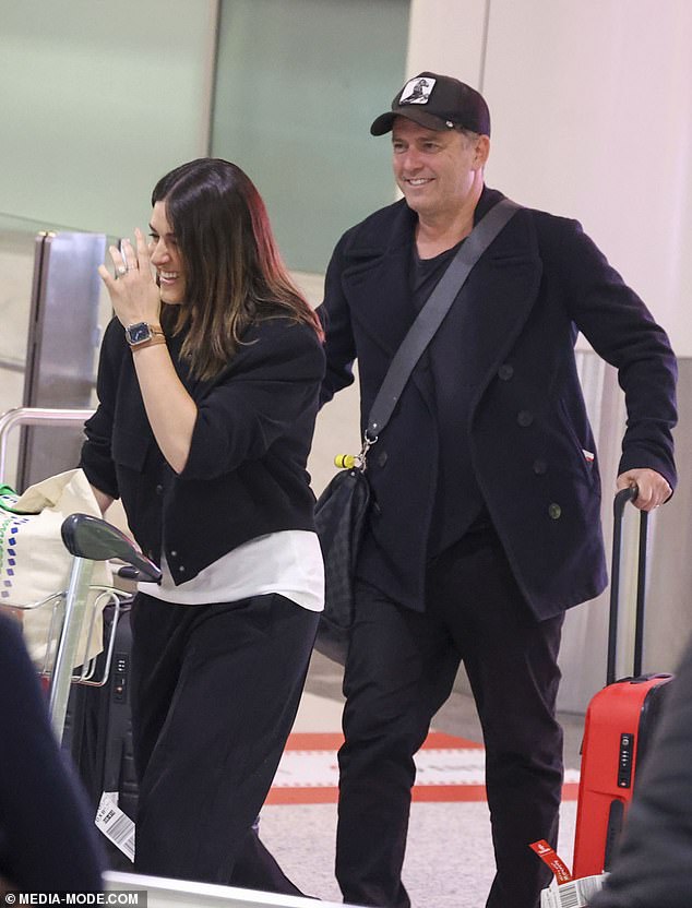 Dressed comfortably for the long flight, Karl wore a pair of black chinos and a simple black shirt under a dark blue duffle coat.