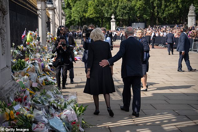 New King Charles places a supportive hand on Camilla's back as the couple view flowers and tributes laid outside Buckingham Palace following the death of Queen Elizabeth, September 2022