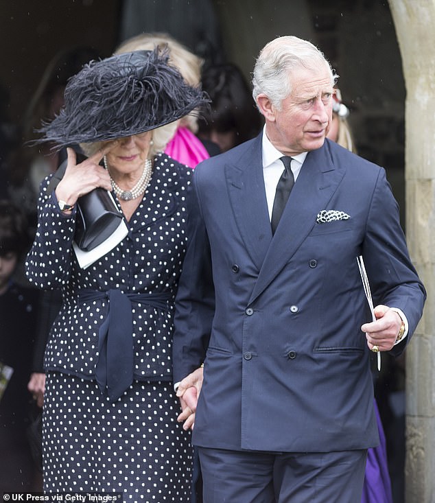 A tearful Camilla, wearing a smart dark polka dot jacket and skirt, holds her husband's hand at the funeral of her brother Mark Shand at a church in Dorset, May 2014.