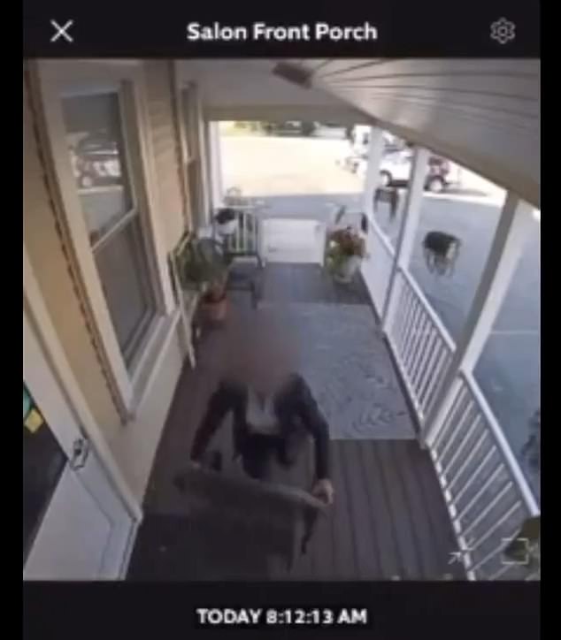 An officer is seen watching the door and camera before using a chair on the porch to stand and cover the camera with tape.