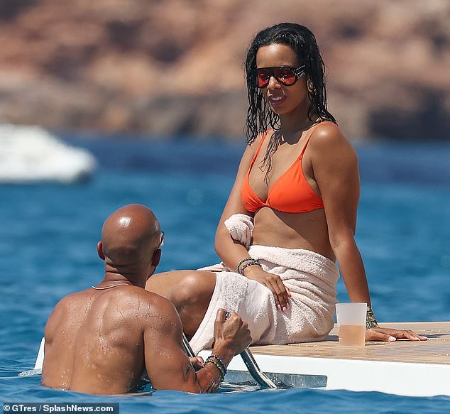 Rochelle wrapped herself in a towel as she watched her handsome husband swim.