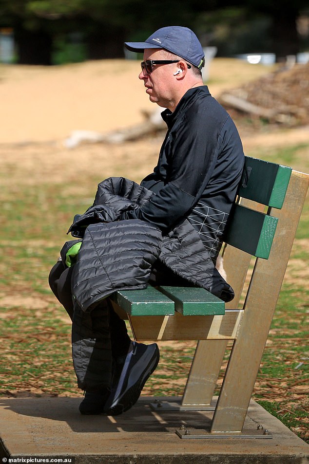 Mr Joyce, wearing a black quilted Kathmandu jacket, cotton tracksuit bottoms and a cap, appeared to be lost in thought as he listened to his AirPods while sitting on a beachside bench.