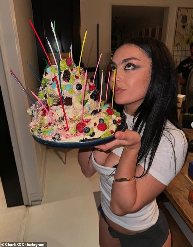 The singer put on a leggy display for the celebrations in a pair of knee-high black boots and accessorised her look with a matching handbag and sunglasses as she posed with her massive cake.