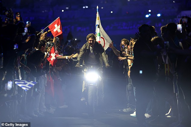 American actor and film producer Tom Cruise carries the IOC flag during the closing ceremony