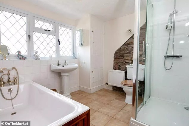 Listing photos show the cottage's traditional stone walls remaining visible in the master bathroom.