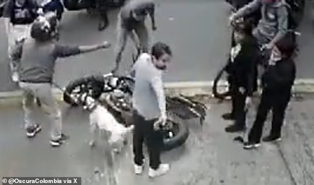 A man holding a dog argues with residents after stopping at the scene where a suspected assailant was brutally beaten in La Magdalena, a neighborhood in Bogota, the capital of Colombia.