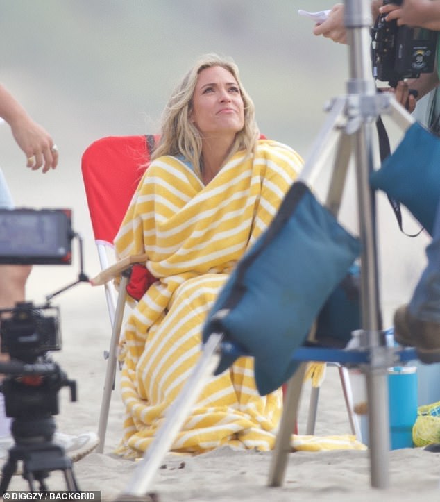 Between takes, she covered herself with a yellow striped blanket to protect herself from the cool ocean air.