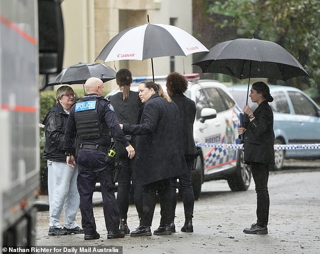 Detectives and police are seen speaking to members of the public at the scene in Carrara.