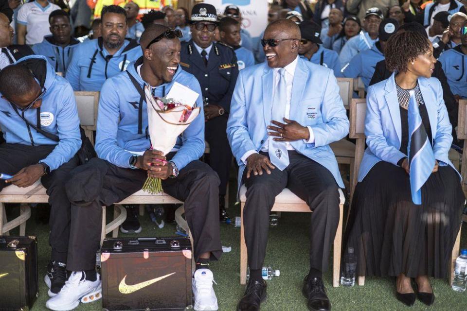 Botswana's President Mokgweetsi Masisi (2nd right) laughs with Olympic gold medallist Letsile Tebogo (2nd left) at the start of a welcome ceremony after winning the men's 200m athletics event during the Paris 2024 Olympic Games, at Sir Seretse Khama International Airport in Gaborone on August 13, 2024. 